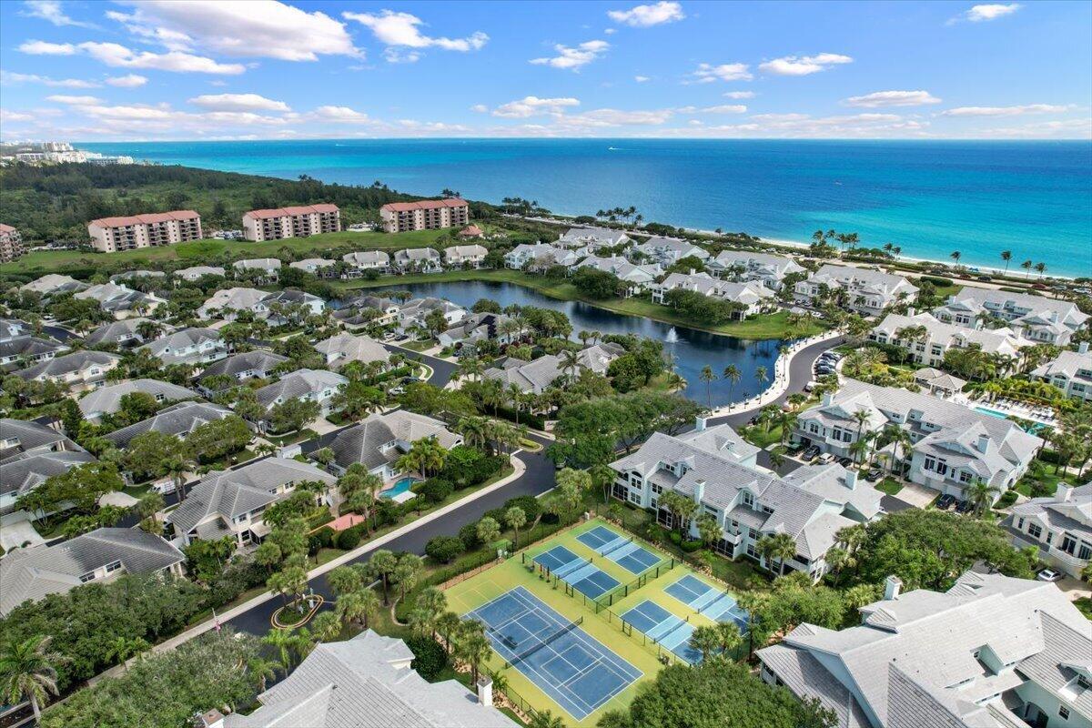 Coastal community with a central lake and tennis courts overlooking the turquoise Atlantic Ocean.