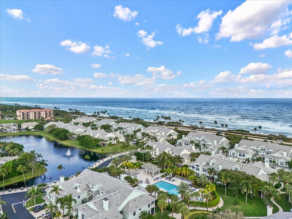 Aerial view of coastal homes, a swimming pool, lagoon, and oceanfront shoreline.