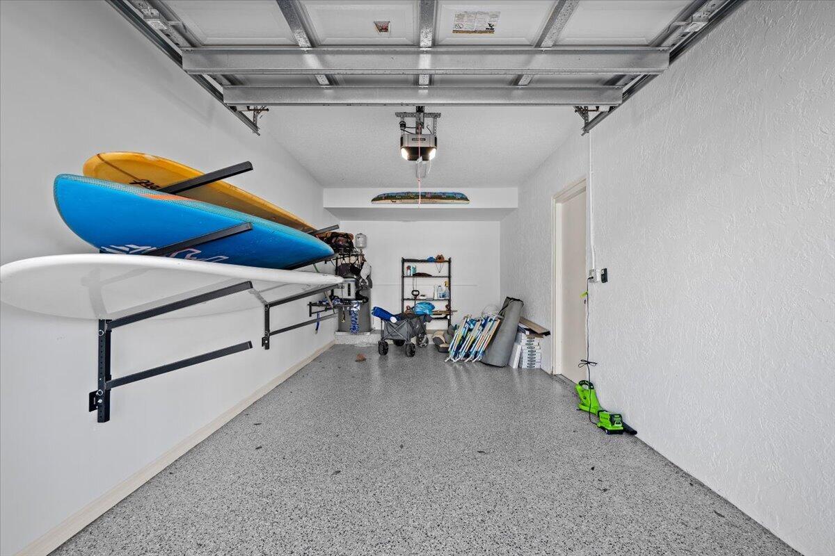 Garage with colorful kayaks mounted on wall racks and beach gear stored at the back.