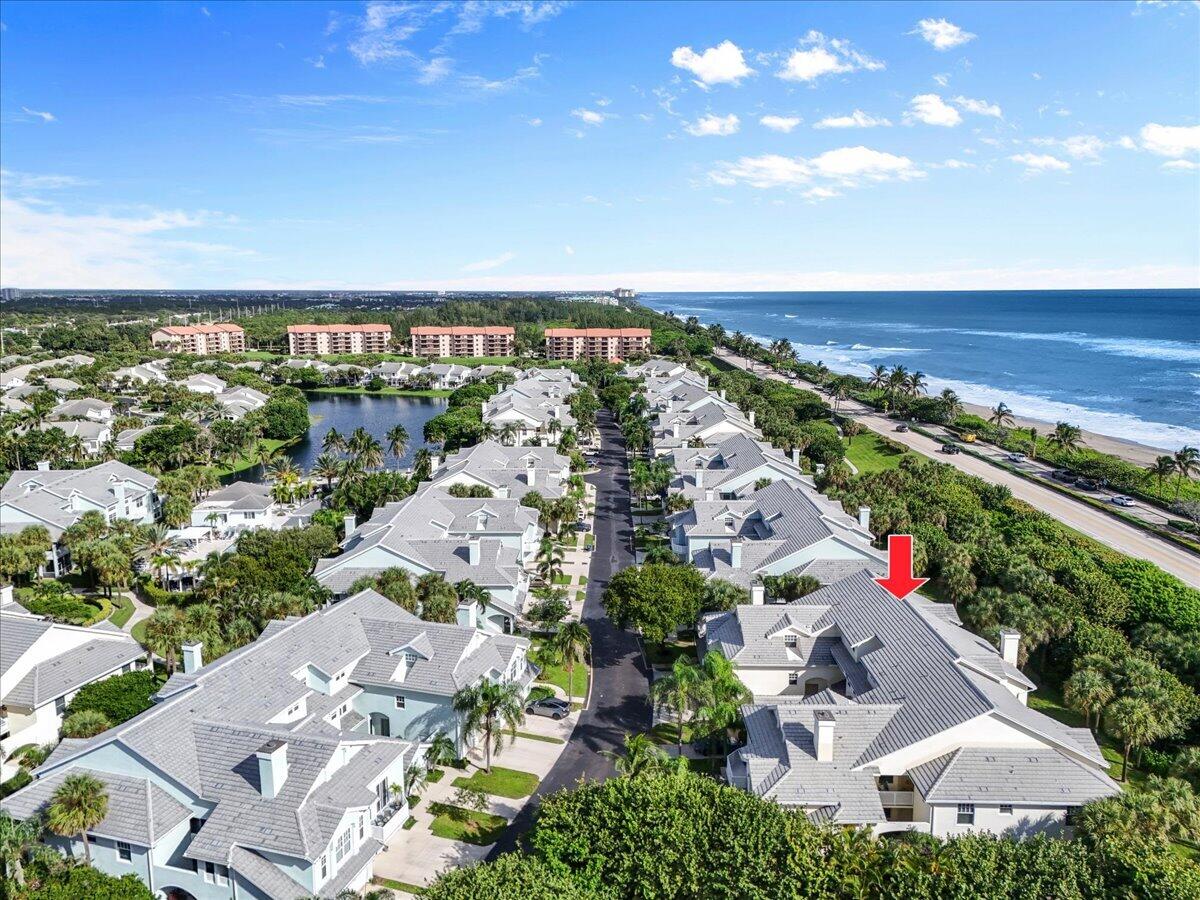 Aerial view of coastal homes, with a red arrow marking one home beside the ocean.
