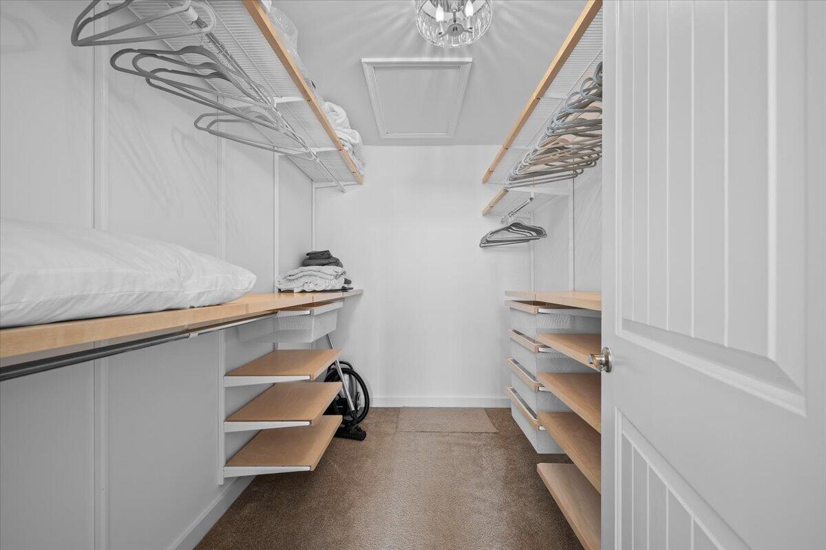 Walk-in closet with wood-tone shelves and drawers, hanging rails, and folded linens.