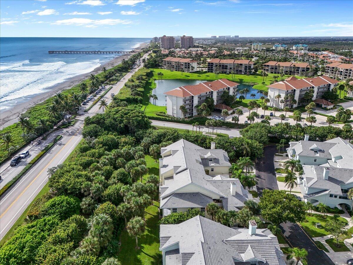 Coastal neighborhood with homes, condominiums, a beach, and ocean pier seen from above.