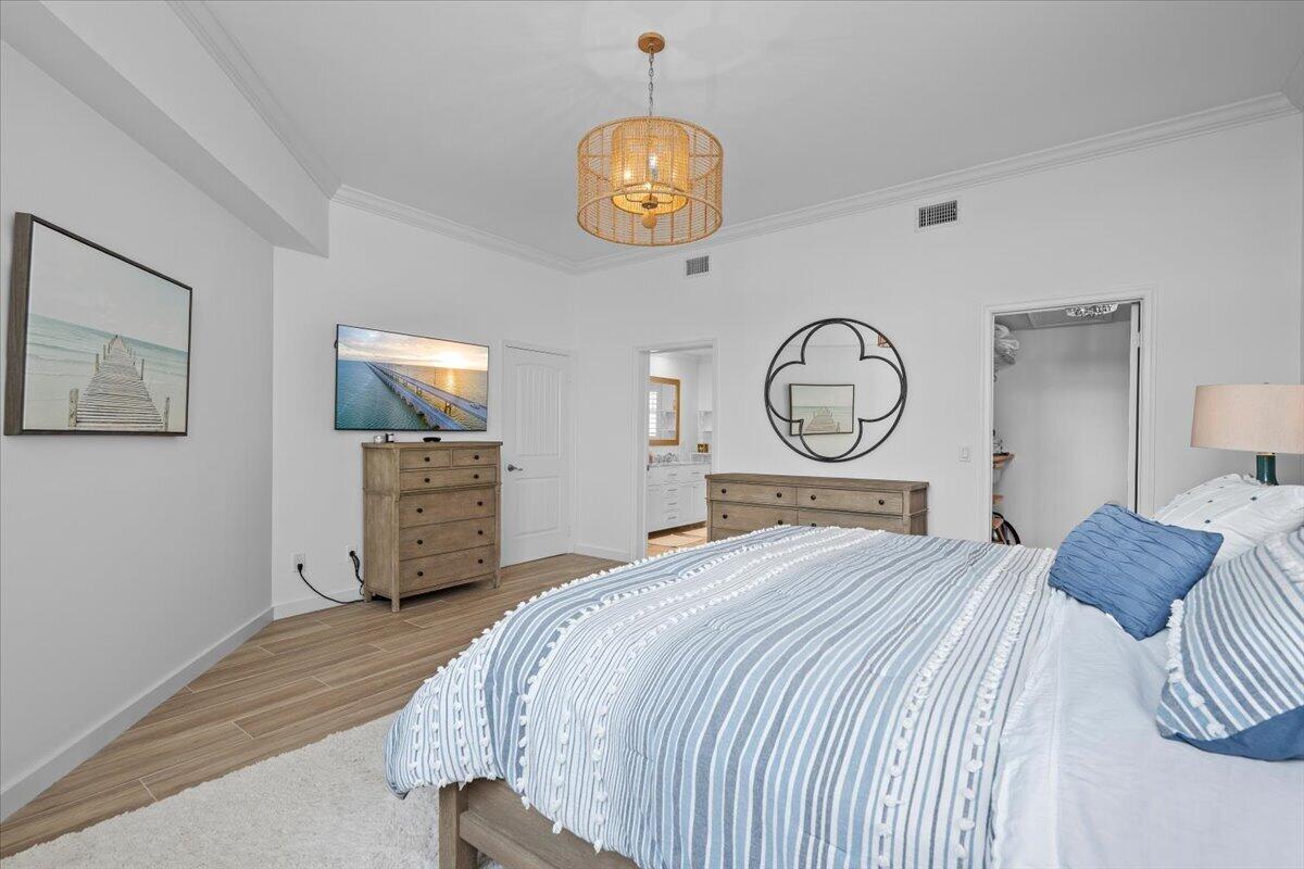 Bedroom with blue-and-white striped bedding, wooden dressers and coastal artwork.