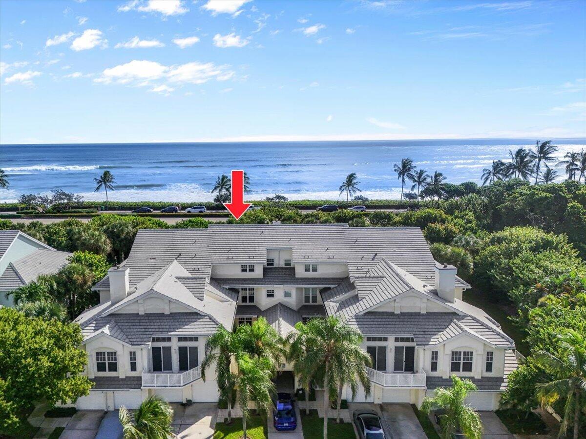 White coastal residential building with a red arrow pointing to it, ocean and beach beyond.