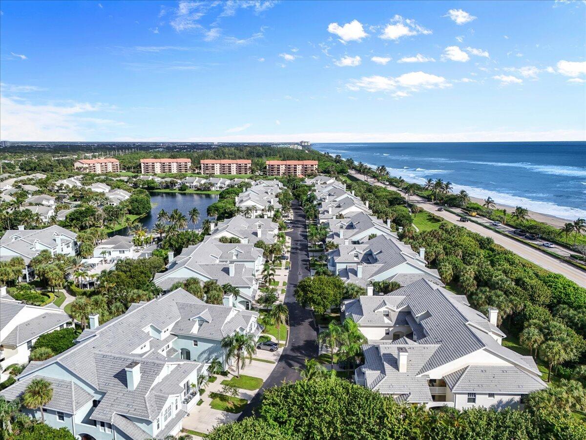 Aerial view of coastal homes, a neighborhood lake, and the Atlantic shoreline.