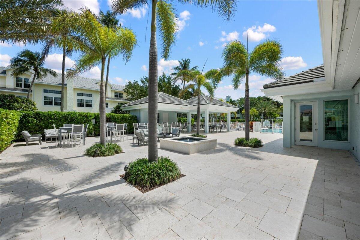 Outdoor courtyard with palm trees, dining tables, a covered pavilion, and a pool.