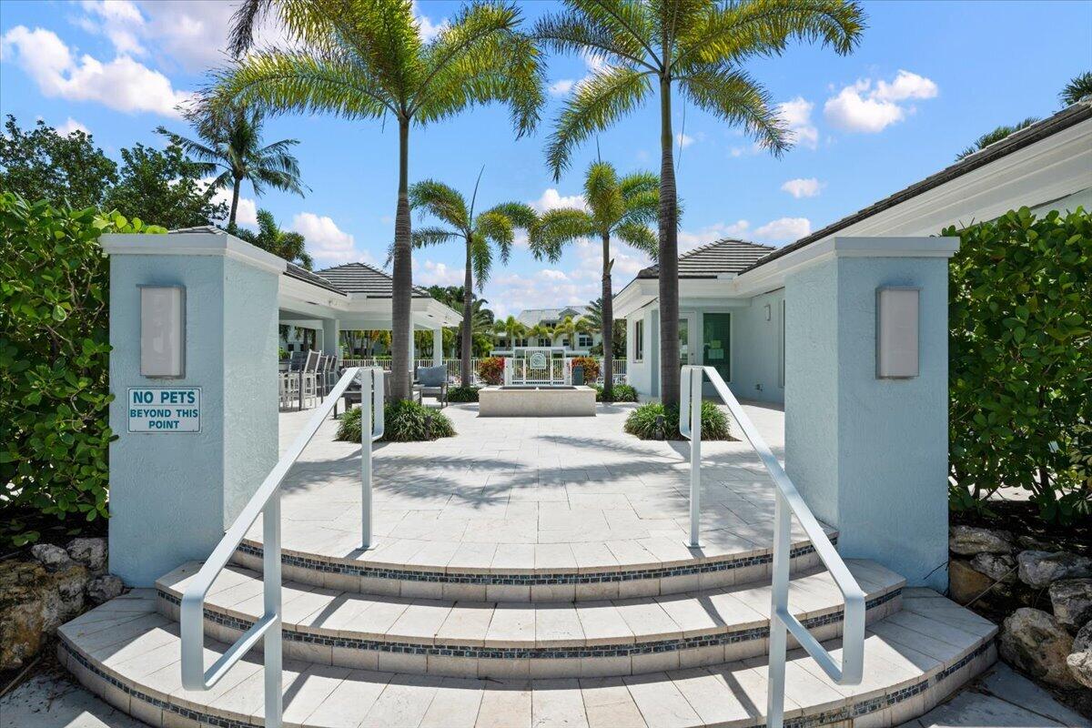 Community courtyard entrance with curved tiled steps, white handrails, and palm trees.