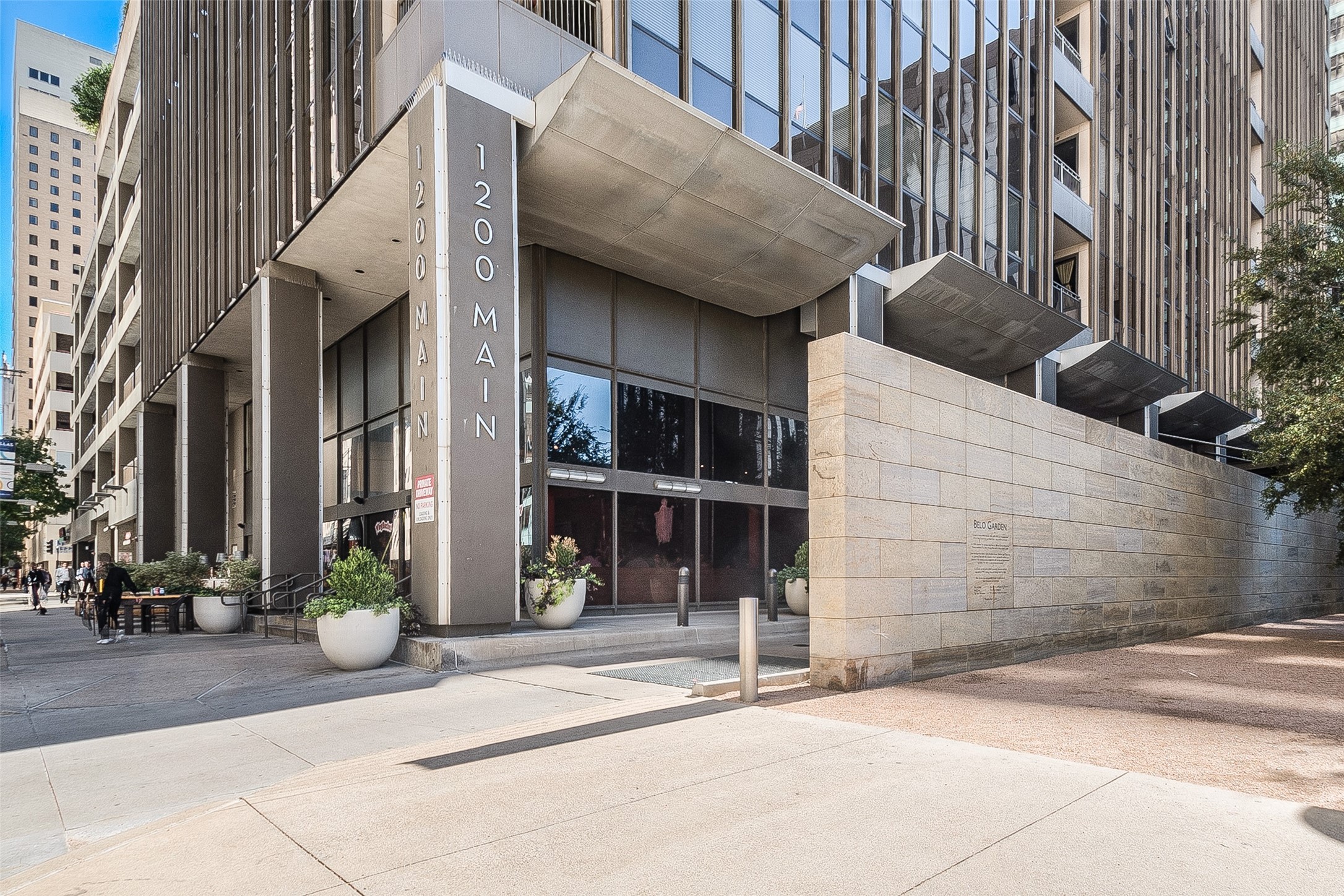 1200 Main high-rise entrance with projecting canopies and the Belo Garden wall.