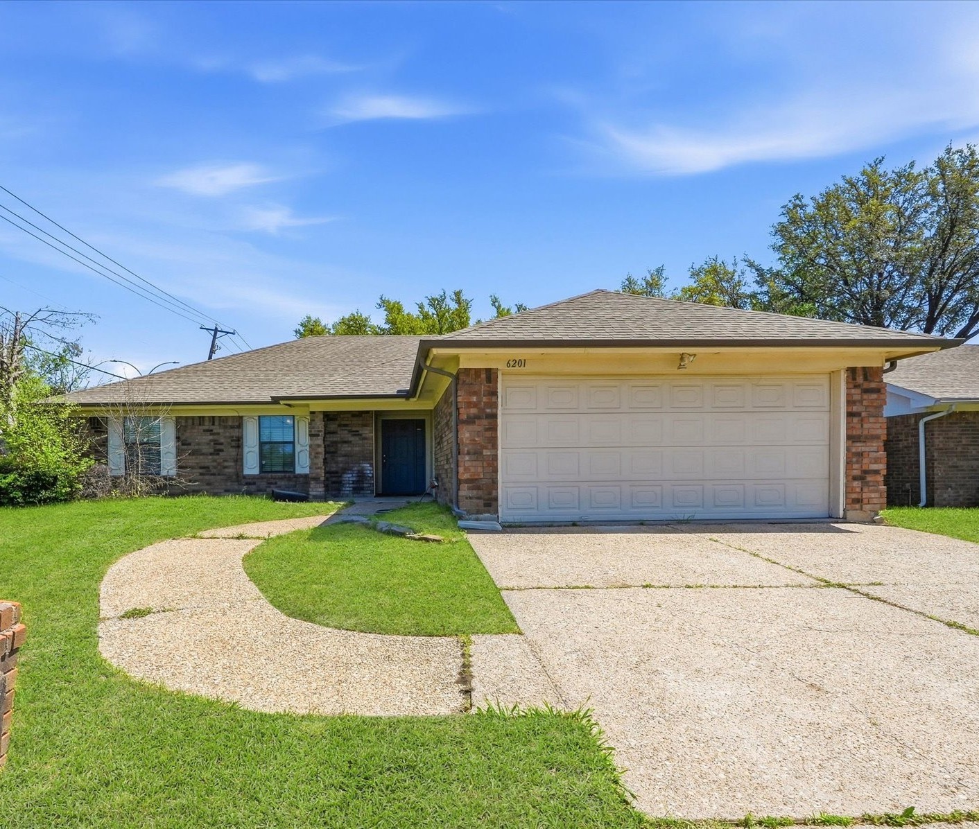 Single-story brick house with a wide garage, blue front door, and curved walkway.