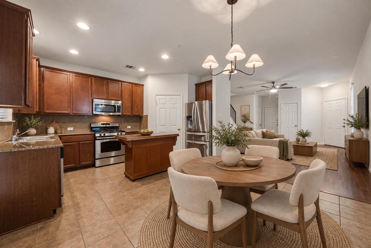 Open-plan kitchen and dining area with dark wood cabinets, stainless appliances, and a round table.