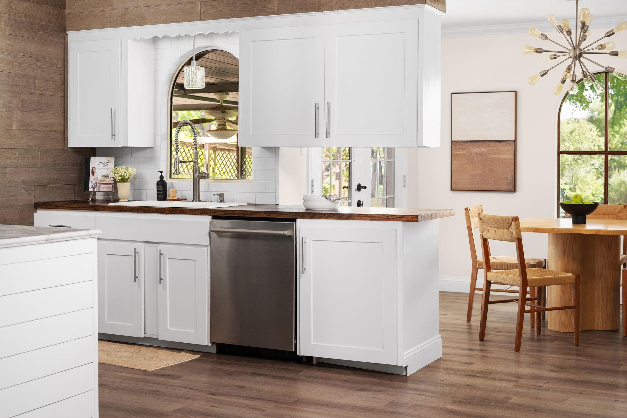 Kitchen with white shaker cabinets, dark wood counters, farmhouse sink, and an adjoining dining area.
