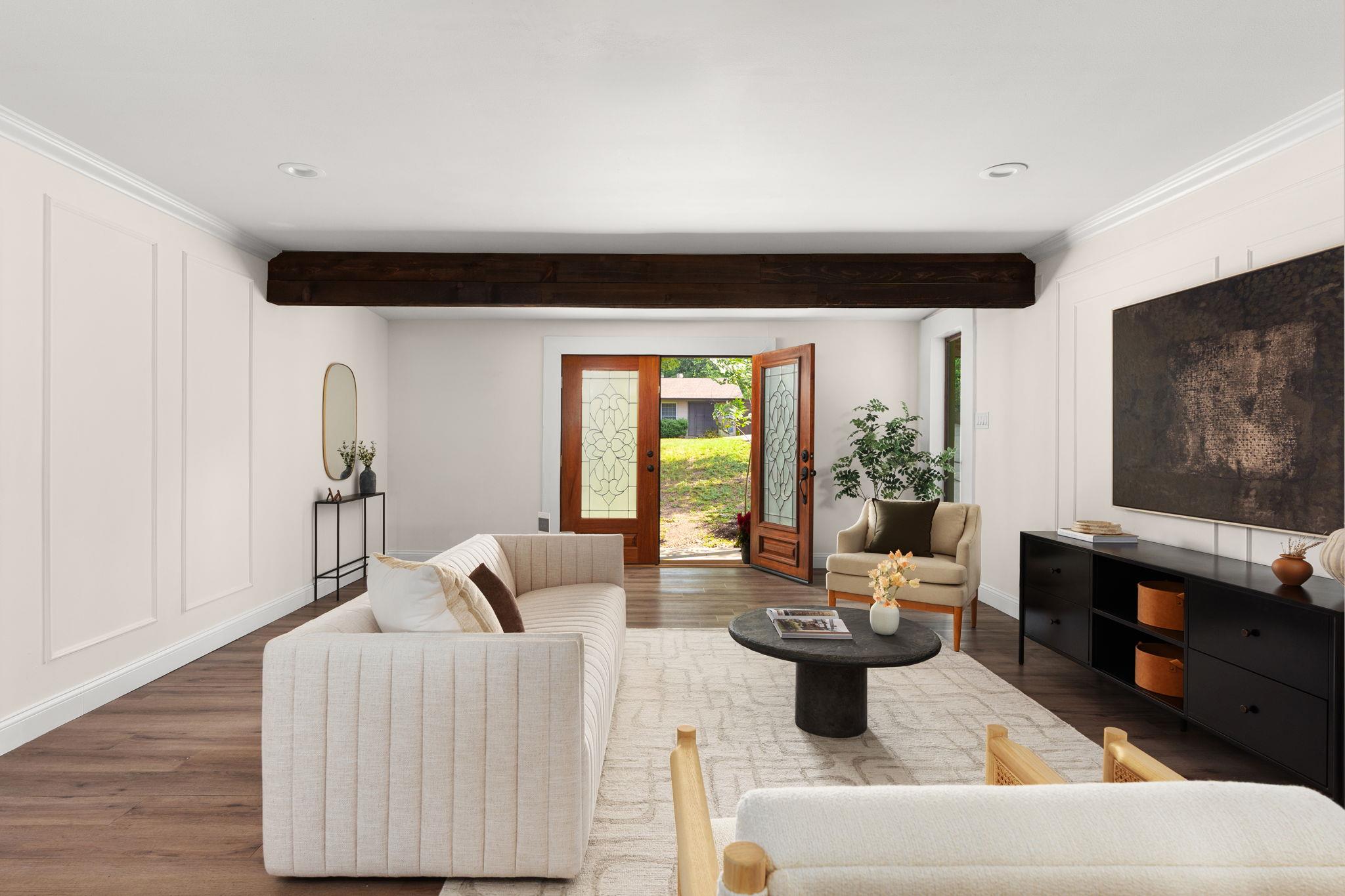 Staged living room with a dark ceiling beam and open decorative glass doors to the yard.