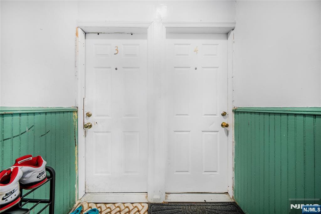 Interior entryway with two numbered white doors and green wainscoting.