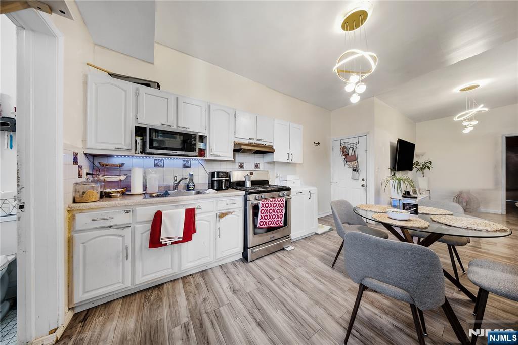 Open-plan kitchen and dining area with white cabinetry, stainless steel appliances, and a round table.
