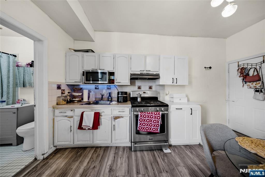 Kitchen with white cabinets, stainless-steel appliances, and a doorway to the bathroom.