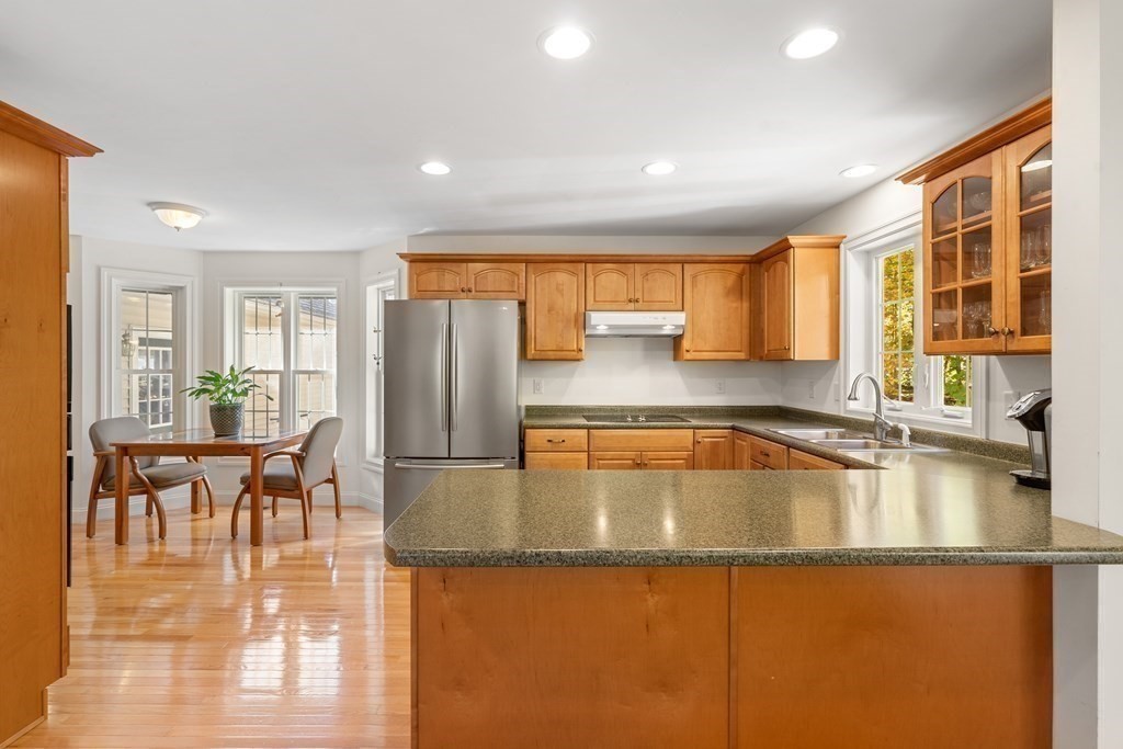 Kitchen with wood cabinets, stainless steel refrigerator, and a large granite-topped island.