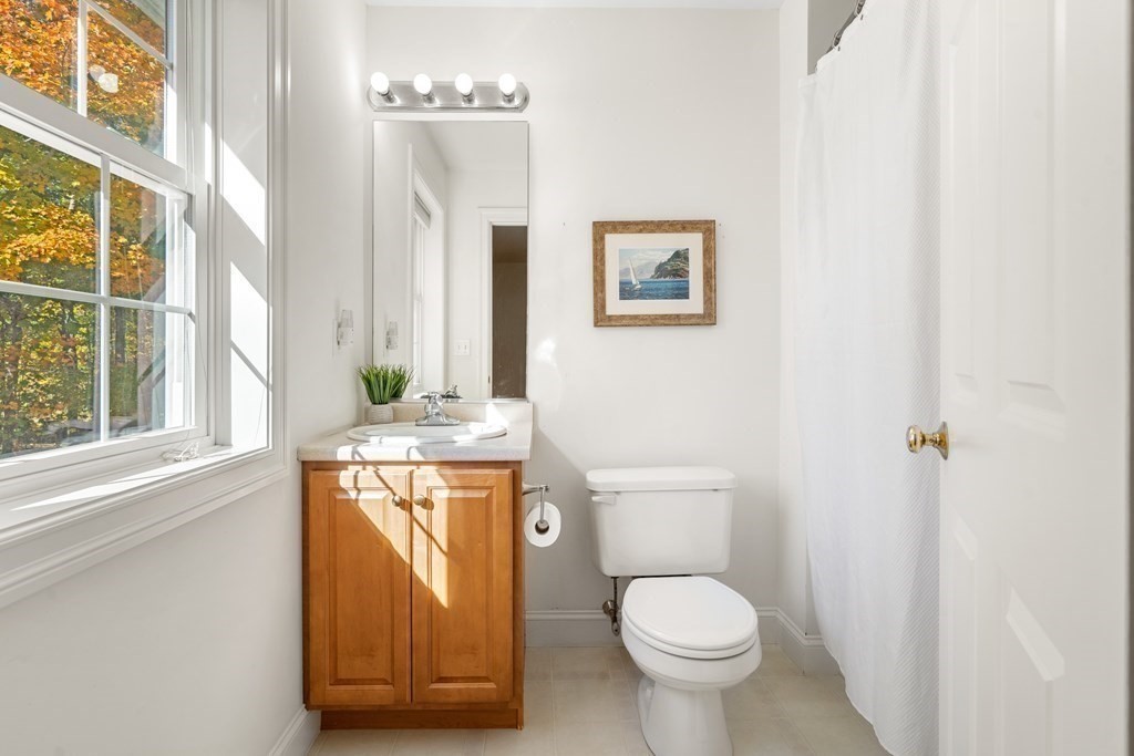 Bright bathroom with a wood vanity and large window overlooking autumn foliage.