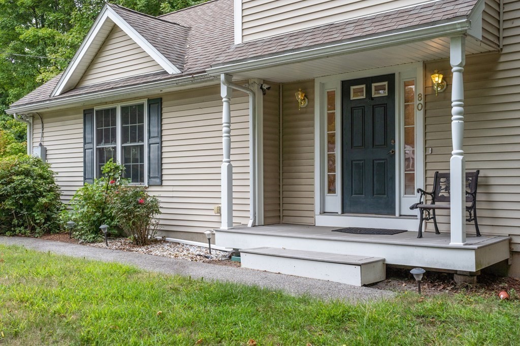 House with a covered front porch, dark entry door, and landscaped yard.