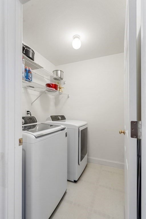 Laundry room with a white washer and dryer beneath wire storage shelves.