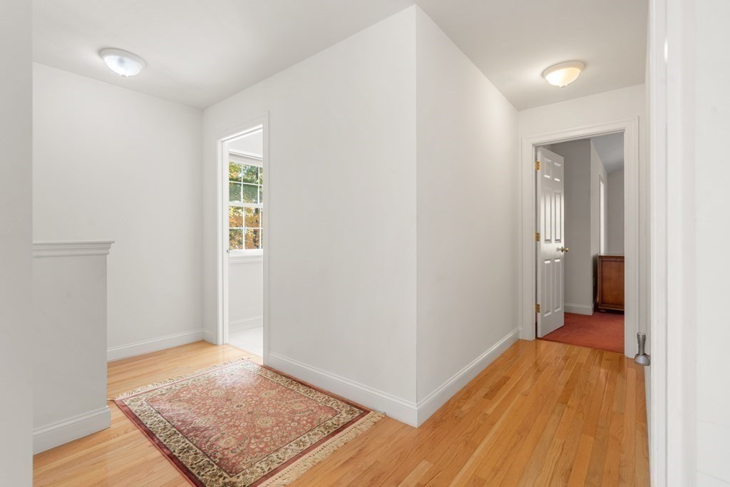 Hallway with hardwood floors, a patterned rug, and doorways to adjoining rooms.