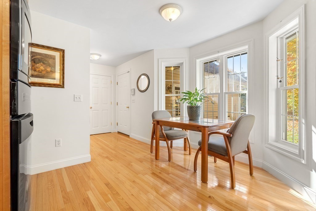 Dining area with a wooden table, upholstered chairs, hardwood floors, and large windows.
