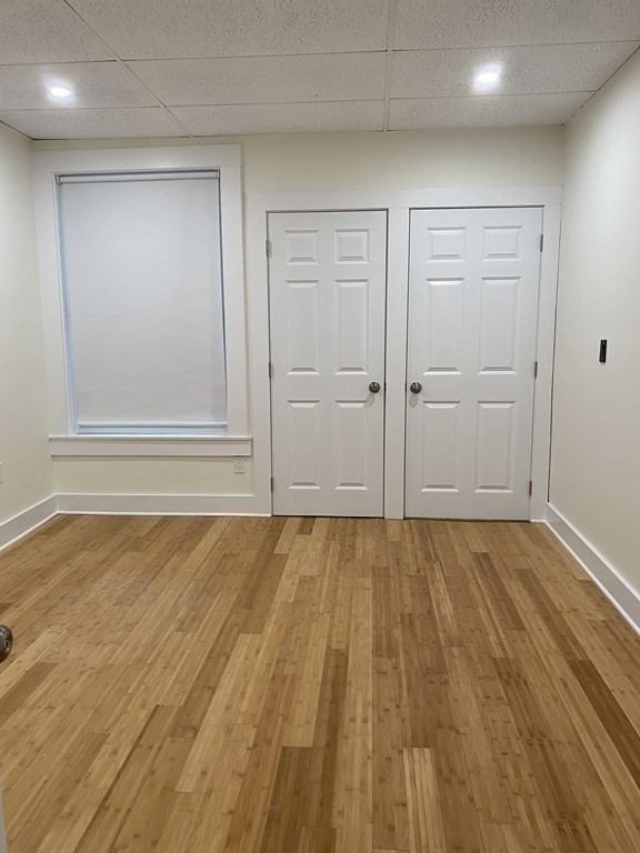 Empty room with light wood flooring, two white paneled doors, and a shaded window.
