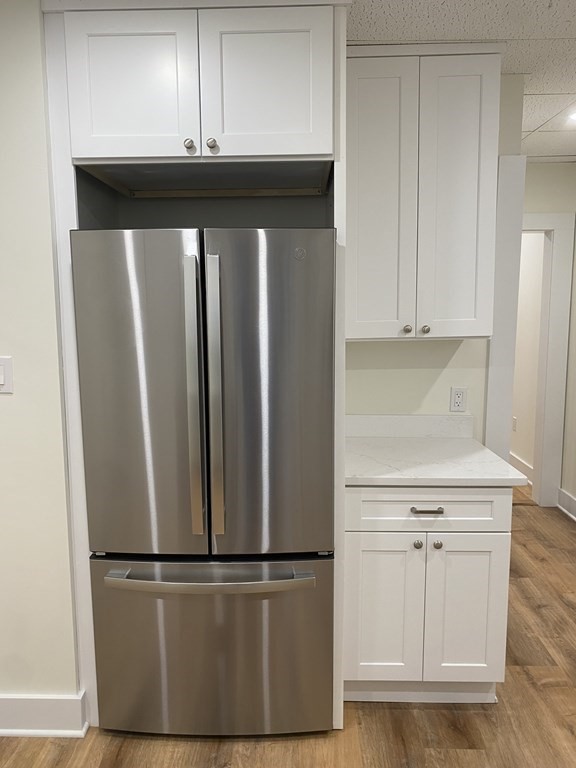 Kitchen with a stainless-steel French-door refrigerator beside white cabinets and a countertop.