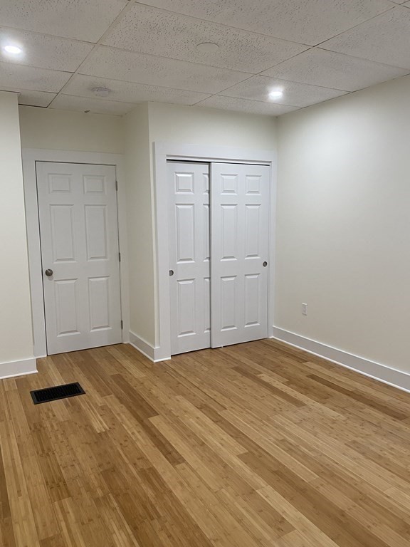 Empty room with light wood flooring, white walls, and paneled doors.