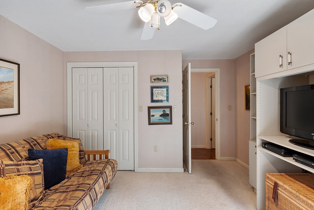 Living room with a patterned sofa, built-in entertainment shelving, and ceiling fan.