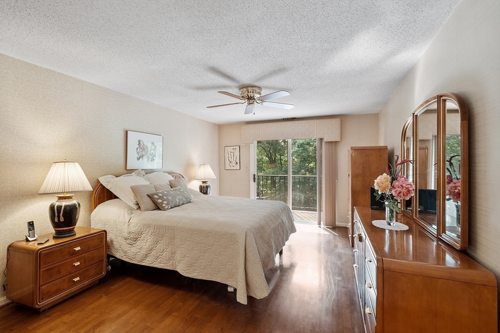 Bedroom with a ceiling fan, hardwood floors, and sliding doors opening to a balcony.