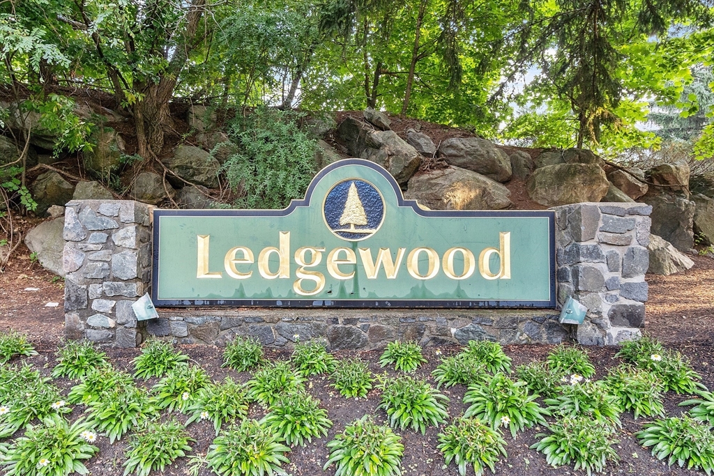 Ledgewood entrance sign in a stone wall, surrounded by landscaped plantings and trees.