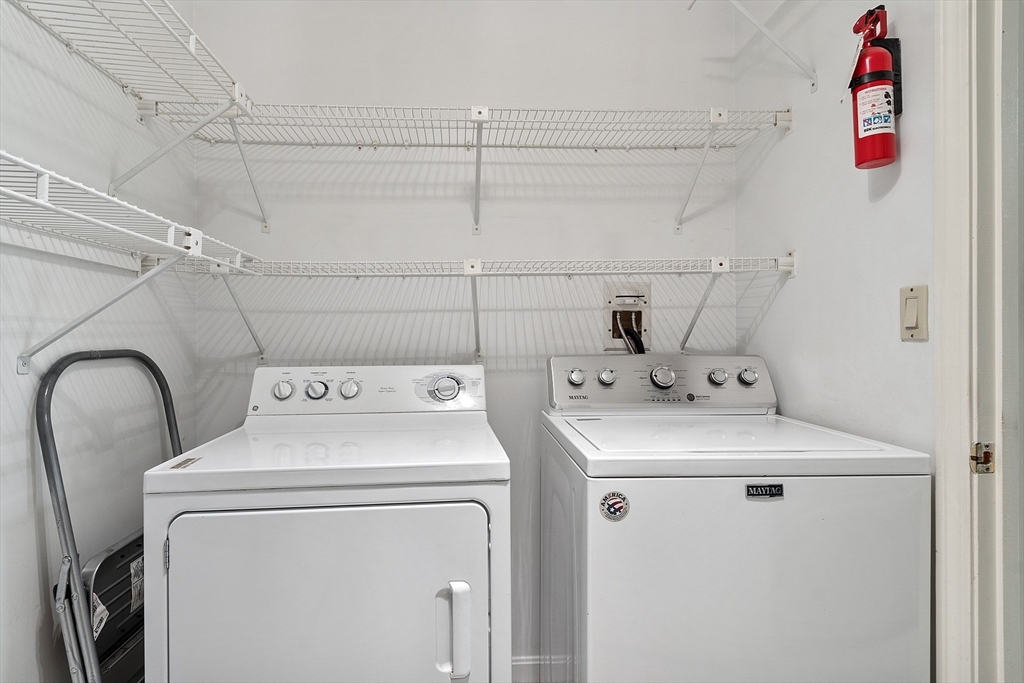 Laundry room with a white Maytag washer and dryer beneath wire shelving.