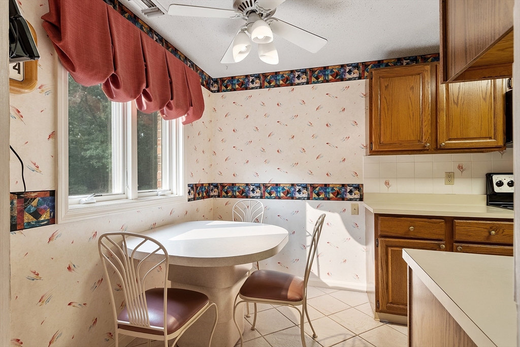 Kitchen with a round dining table beside two windows and honey-colored wood cabinets.