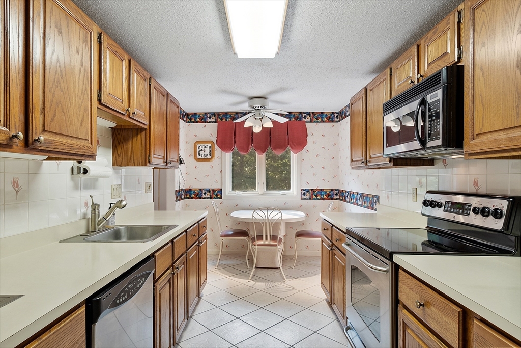Kitchen with wood cabinets, stainless appliances, and a small dining nook by the window.