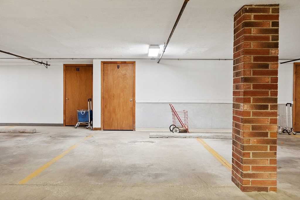 Parking garage with yellow-marked spaces, wooden doors, and a brick support column.