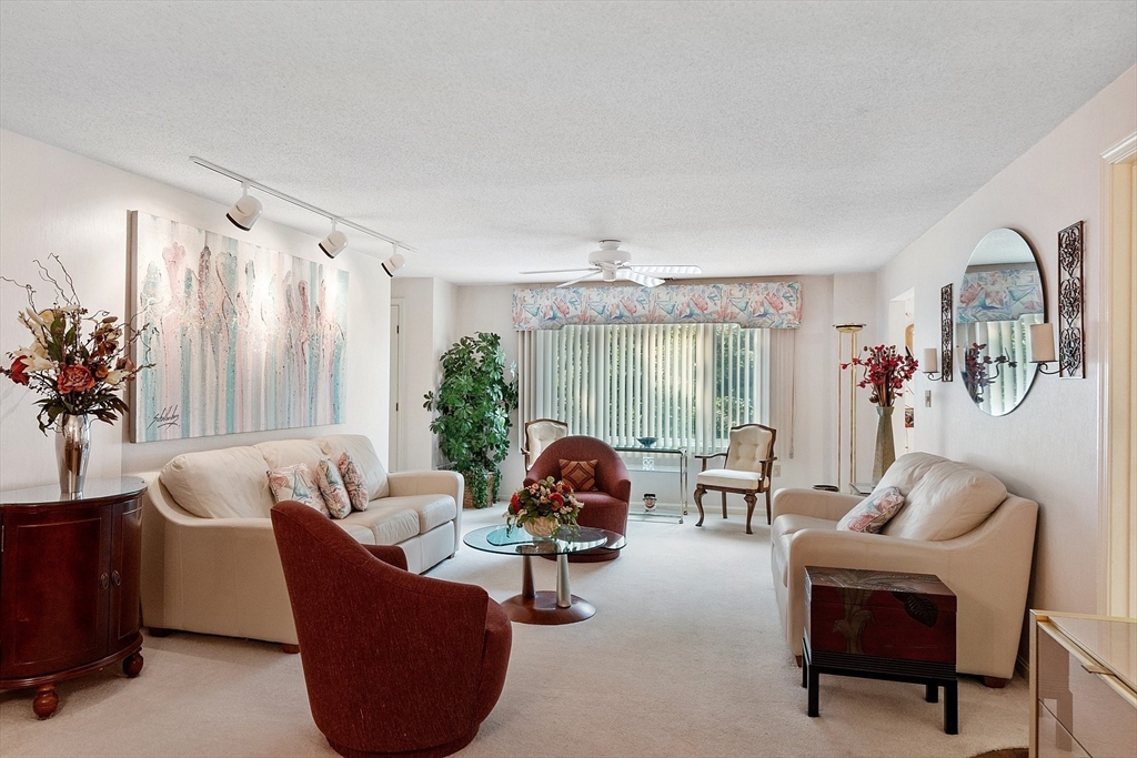 Living room with cream sofas, burgundy chairs, abstract art, and sliding glass doors.