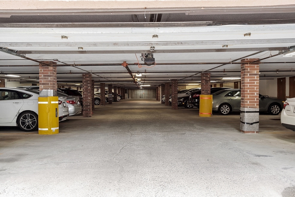 Shared parking garage with parked cars and brick support pillars.