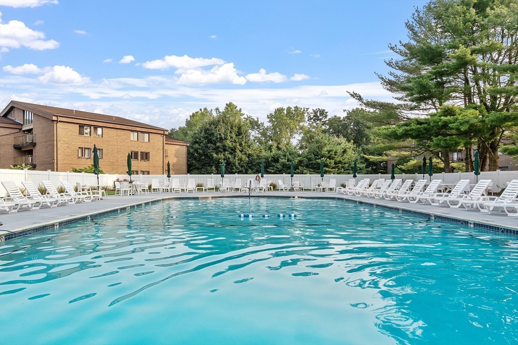 Residential complex pool with turquoise water and rows of white lounge chairs.