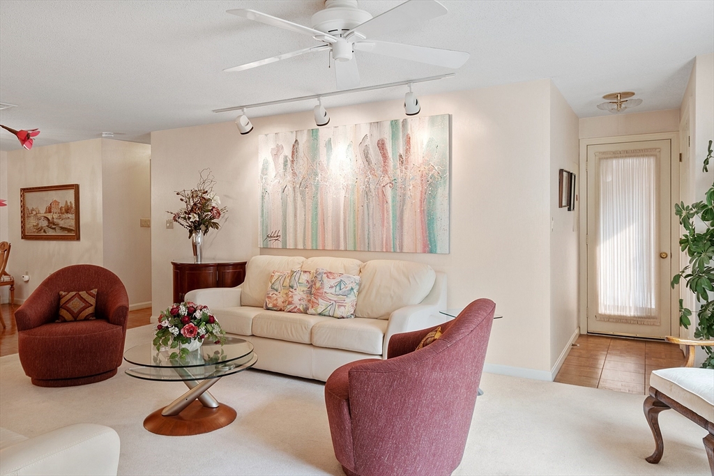 Living room with a white sofa, burgundy armchairs, and large pastel artwork.