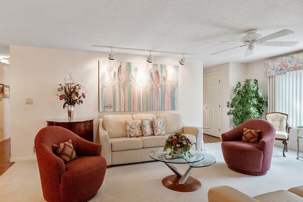 Living room with a cream sofa, rust-colored armchairs, glass coffee table, and large abstract painting.