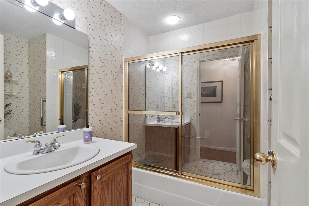 Bathroom with a wood vanity and gold-framed sliding glass shower doors.