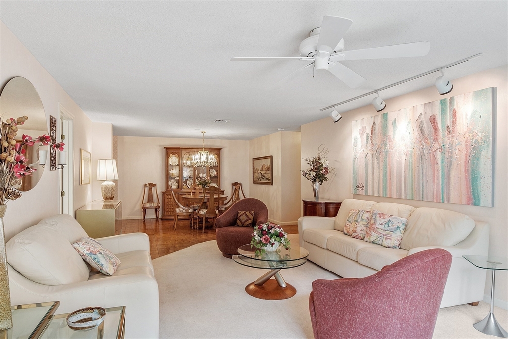 Living and dining area with white sofas, pink accent chairs, and large abstract wall art.