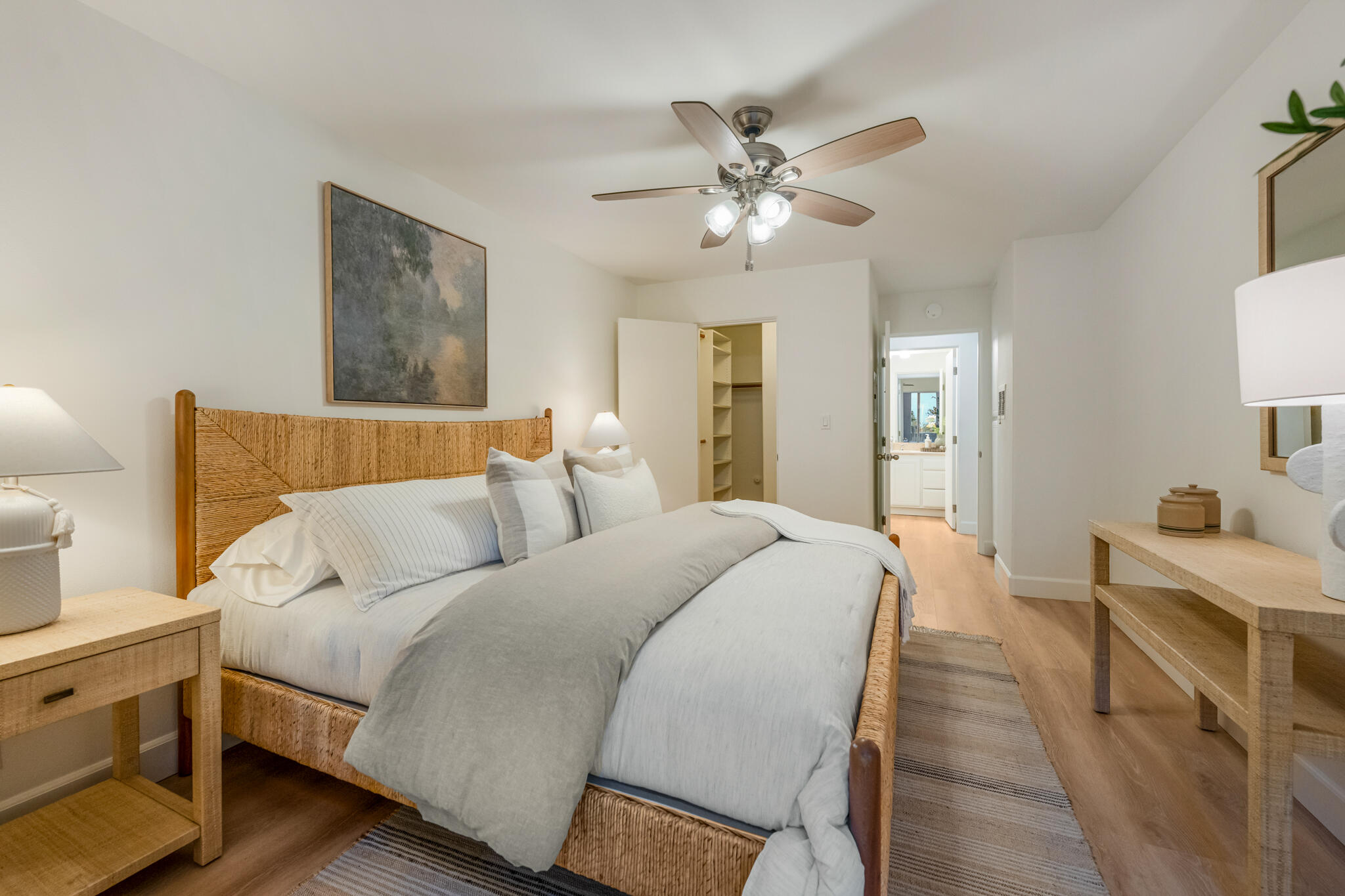 Bedroom with a woven rattan bed, gray-and-white bedding, and an open closet.
