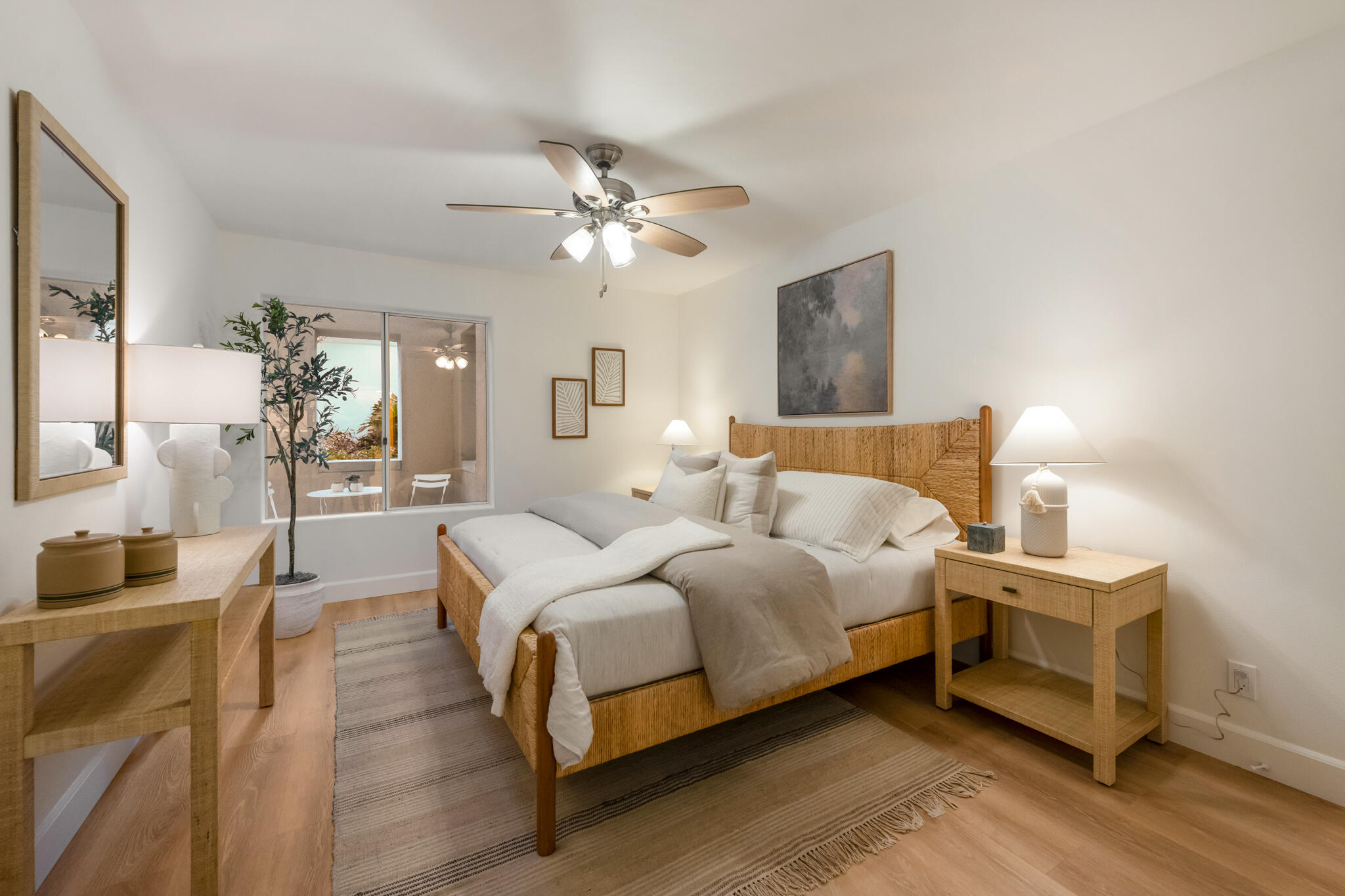 Staged bedroom with a woven wood bed, neutral bedding, and sliding glass doors to a patio.