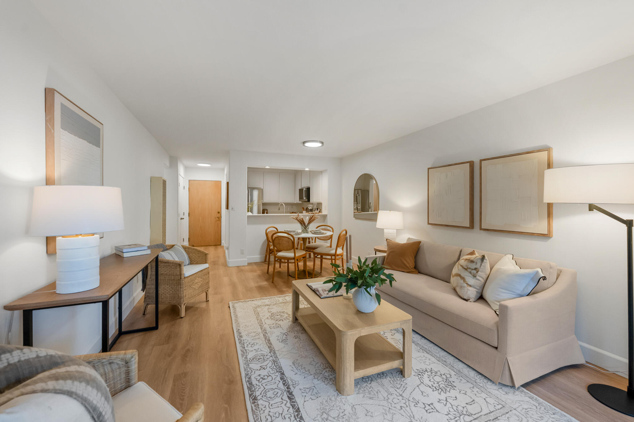 Open-plan living room with beige sofa, wood coffee table, and dining area beside the kitchen.