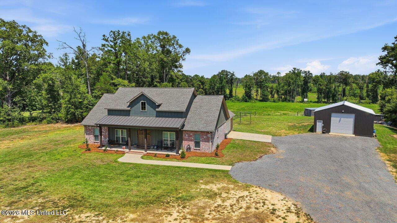 Rural home with a covered porch and detached metal workshop, viewed from above.