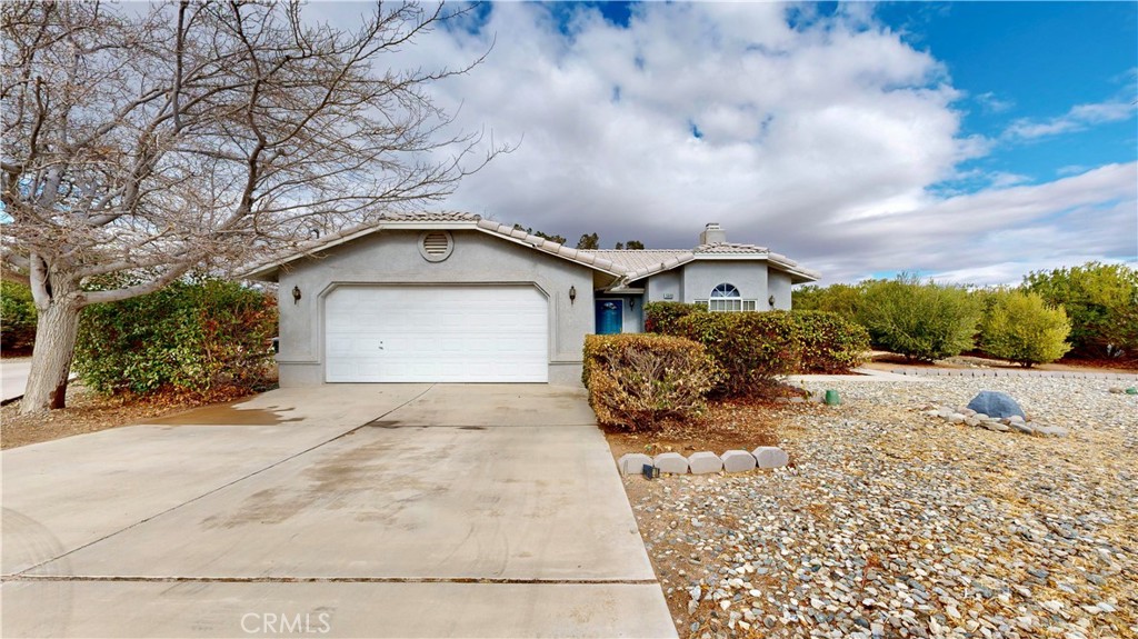 Single-story home with an attached garage, broad driveway, and drought-tolerant rock landscaping.