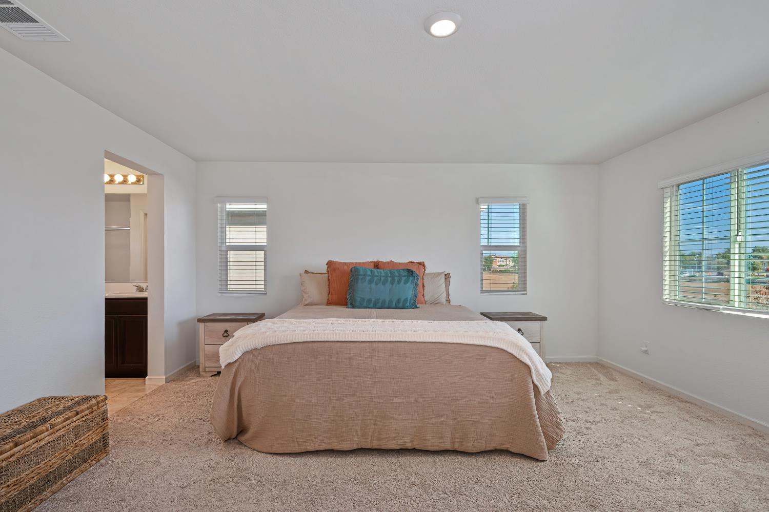 Staged bedroom with a large bed, bedside tables, and windows on three sides.