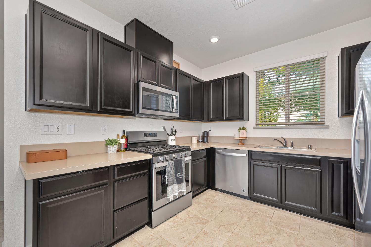 Kitchen with dark cabinets, stainless steel appliances, and a sink beneath a window.