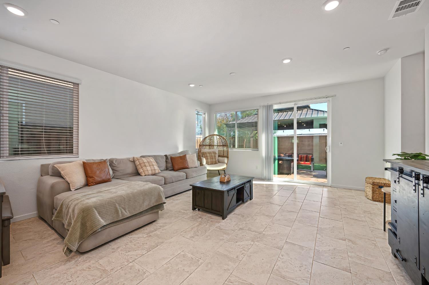 Staged living room with a gray sectional, tiled floor, and sliding glass door to the patio.